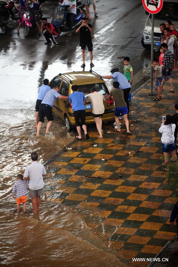 Citizens and policemen help to push a car on a flooded road in Liuzhou City, south China's Guangxi Zhuang Autonomous Region, June 10, 2013. Lingering heavy rainfalls in recent days has caused the Liujiang River's water level to rise to 82.7 meters in urban Liuzhou by 11 a.m. Beijing Time (0300 GMT) on Monday, 0.2 meters higher than the warning level. (Xinhua/Huang Xiaobang) 