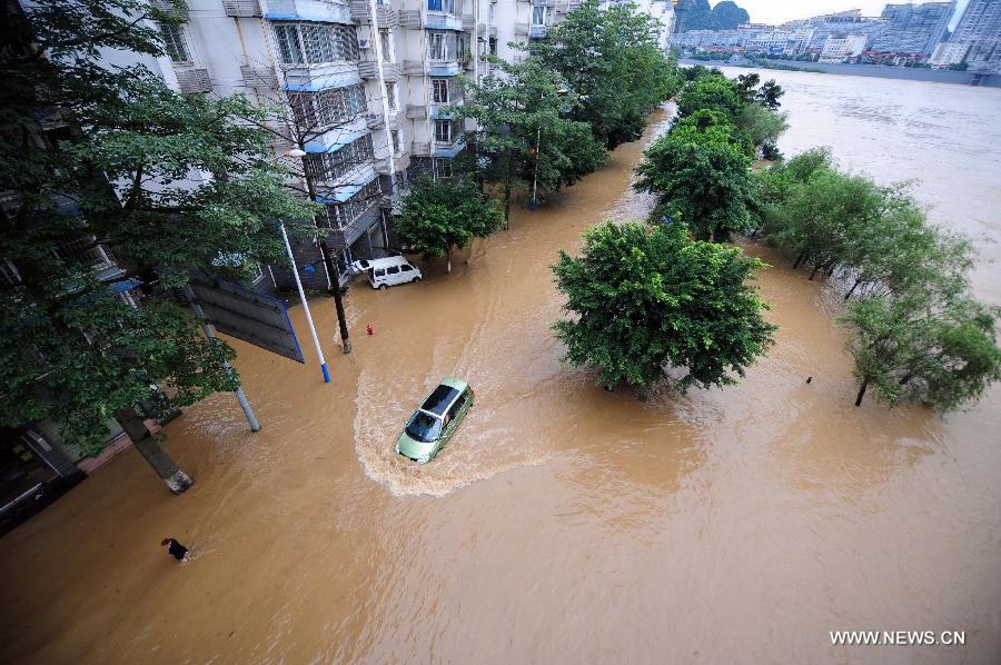 A vehicle moves on a flooded road in Liuzhou City, south China's Guangxi Zhuang Autonomous Region, June 10, 2013. Lingering heavy rainfalls in recent days has caused the Liujiang River's water level to rise to 82.7 meters in urban Liuzhou by 11 a.m. Beijing Time (0300 GMT) on Monday, 0.2 meters higher than the warning level. (Xinhua/Huang Xiaobang)