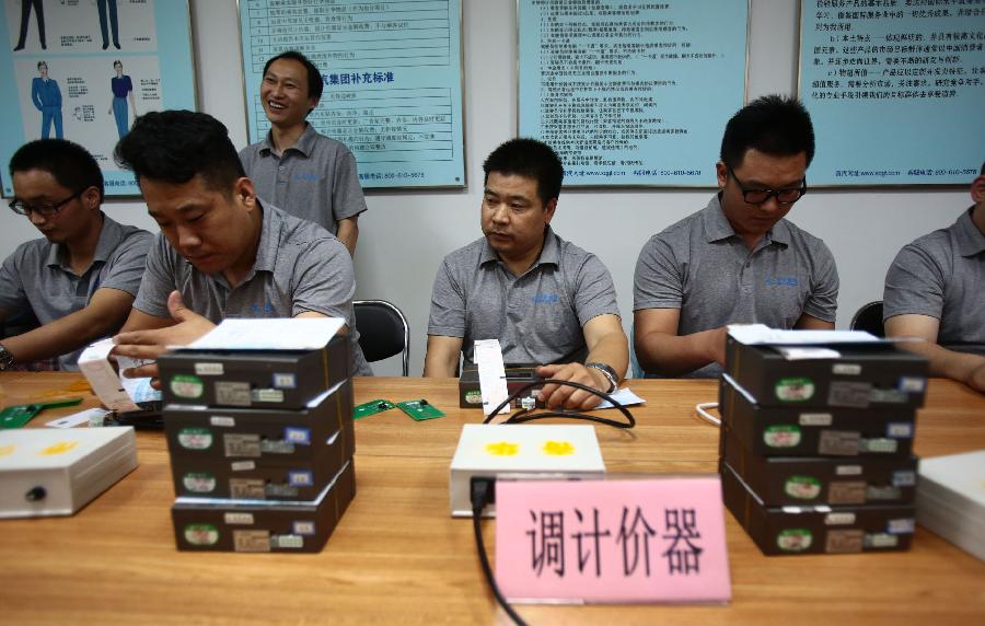 Working staff adjust taximeters according to the latest fare hike in Beijing, capital of China, June 9, 2013. The 3-kilometer base fare for a taxi in Beijing rose by 30 percent from 10 yuan (1.6 U.S. dollars) to 13 yuan as of Monday. According to the new plan, a cab fare will be charged at 2.3 yuan per kilometer after the first 3 kilometers. (Xinhua/Li Wen)