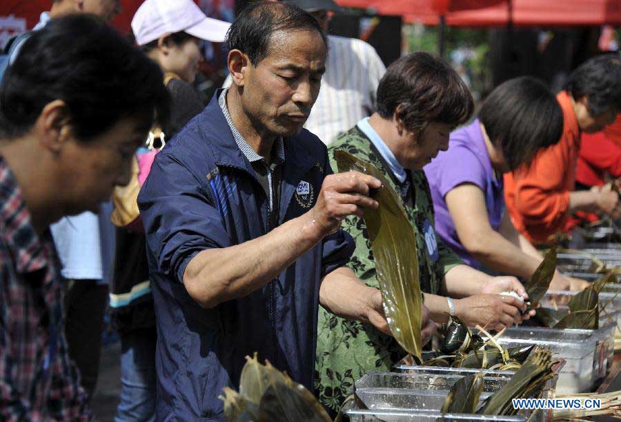 Competitors make Zongzi, a pyramid-shaped dumpling made of glutinous rice wrapped in bamboo or reed leaves, at a cultural festival during the Dragon Boat Festival holiday in Beijing, capital of China, June 10, 2013. The festival, which is held across China to pay homage to Qu Yuan, a patriot poet during the Warring State Period (475-221 BC), falls on the fifth day of the fifth month in the Chinese lunar calendar, or June 12 this year. (Xinhua/Li Xin) 