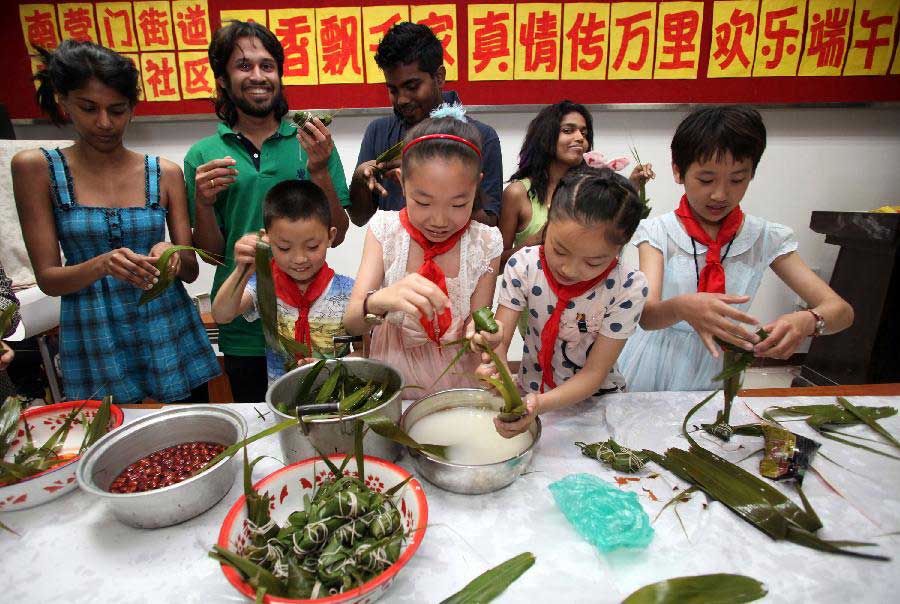 Foreign students of Tianjin Medical University join local residents in making zongzi, a pyramid-shaped dumpling made of glutinous rice wrapped in bamboo or reed leaves, to celebrate the upcoming Dragon Boat (Duanwu) Festival in Tianjin, north China, June 9, 2013. The Duanwu Festival falls on the fifth day of the fifth month in the Chinese lunar calendar, or June 12 this year. (Xinhua/Liu Dongyue) 