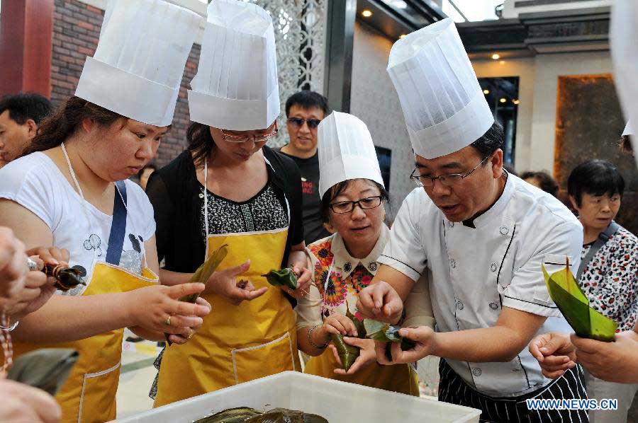 Competitors make zongzi, a pyramid-shaped dumpling made of glutinous rice wrapped in bamboo or reed leaves, at a contest during the Dragon Boat (Duanwu) Festival holiday in Changchun, capital of northeast China's Jilin Province, June 10, 2013. The Duanwu Festival, which is celebrated across China to pay homage to Qu Yuan, a patriotic poet during the Warring State Period (475-221 BC), falls on the fifth day of the fifth month in the Chinese lunar calendar, or June 12 this year. (Xinhua/Zhang Nan)  