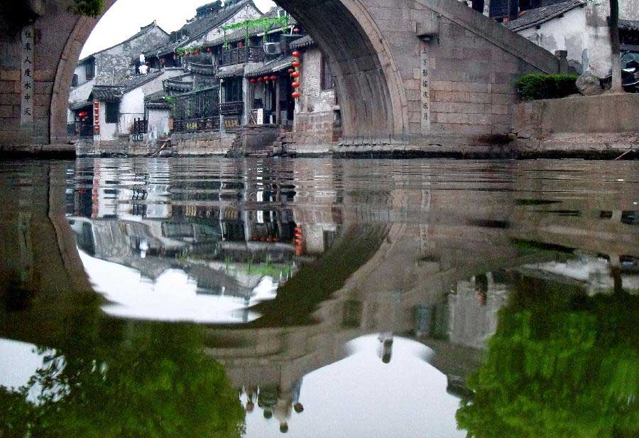 An arch bridge is reflected on water in Xitang ancient town of Jiashan County, east China's Zhejiang Province, April 21, 2011. (Xinhua/Wang Song)