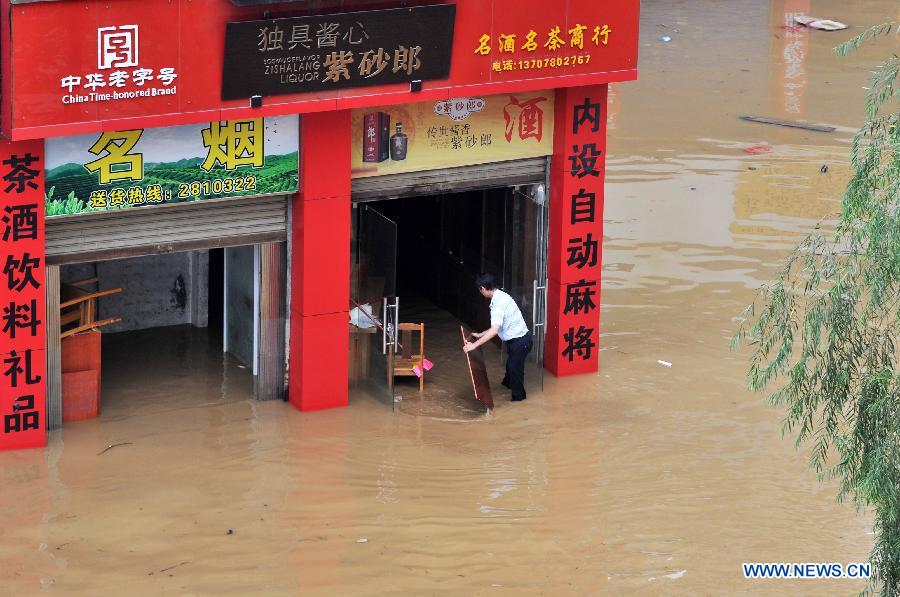 A man carries goods in a flooded street in Liuzhou City, south China's Guangxi Zhuang Autonomous Region, June 11, 2013. Liujiang River's water level surpassed the warning line in urban Liuzhou on Monday, and started to descend in the night after the flood peak. (Xinhua/Li Bin)