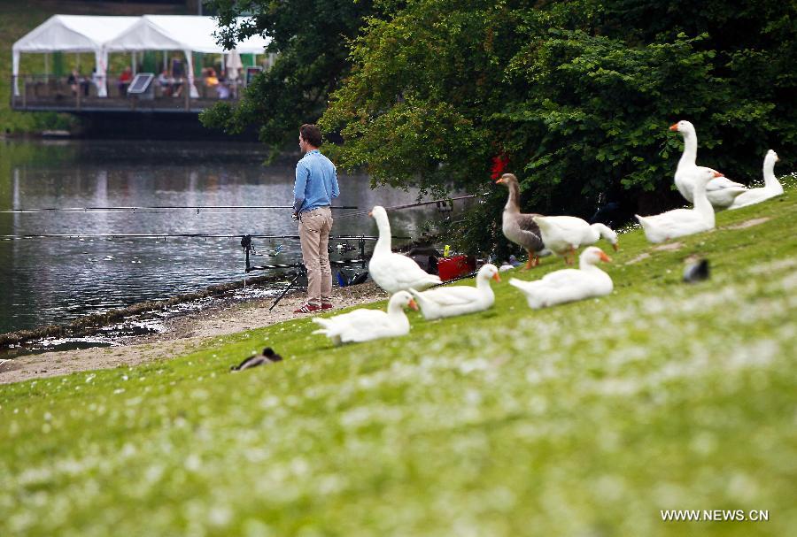 A man fishes at a park in the eastern suburbs of Brussels, capital of Belgium, on June 11, 2013. Local residents go to parks to enjoy the sunshine after experiencing a long and gloomy spring this year. (Xinhua/Zhou Lei)