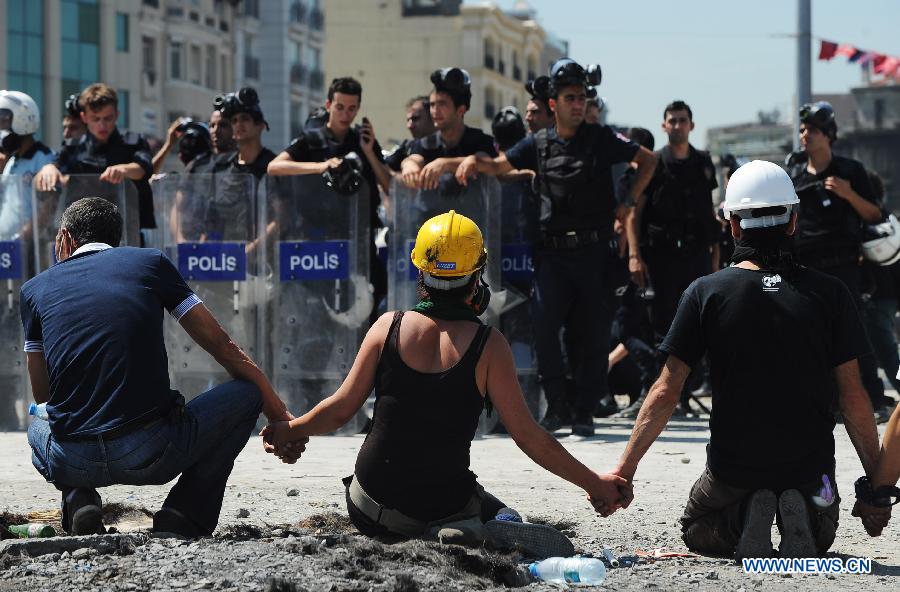 Demonstrators confront with police in the Taksim Square in Istanbul, Turkey, on June 11, 2013. Turkish riot police fired water cannon and teargas at hundreds of protesters in Istanbul's Taksim Square on Tuesday, entering the square for removing the roadblocks and cleanning up flags and banners. Demonstrators fought back with stones and fireworks. (Xinhua/Lu Zhe)