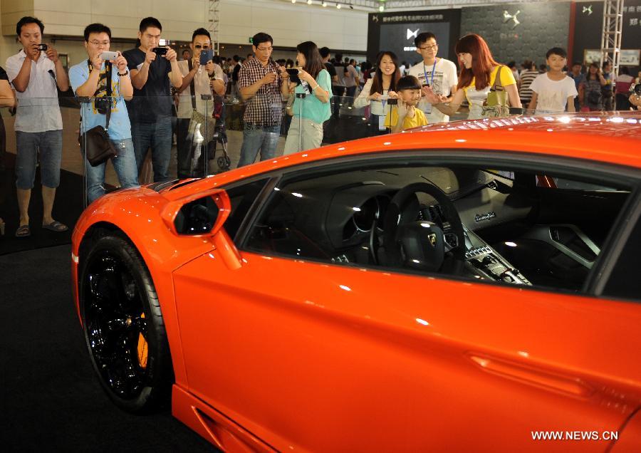 Visitors take pictures of a Lamborghini sports car at the 2013 Central China International Auto Expo in Zhengzhou, capital of central China's Henan Province, June 12, 2013. The five-day expo kicked off here on Wednesday. (Xinhua/Li Bo)