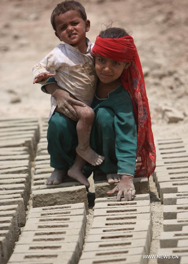 An Afghan girl holds her brother as she displays bricks at a brick factory in Kabul, Afghanistan on June 12, 2013. Afghan labor children work as usual on June 12 while many countries around the world mark the day as the World Day Against Child Labor. The International Labor Organization (ILO) launched the World Day Against Child Labor in 2002, which falls on each June 12. (Xinhua/Ahmad Massoud) 