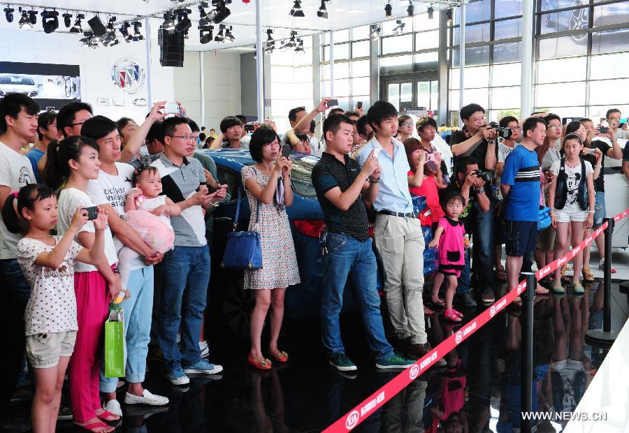 People watch models performing at 2013 Xi'an International Automobile Industry Exposition in Xi'an, capital of northwest China's Shaanxi Province, June 12, 2013. Visiting the auto show, which lasts from June 8 to 17, is the way many local residents spent their three-day Dragon Boat Festival vacation from June 10 to 12. (Xinhua/Ding Haitao)