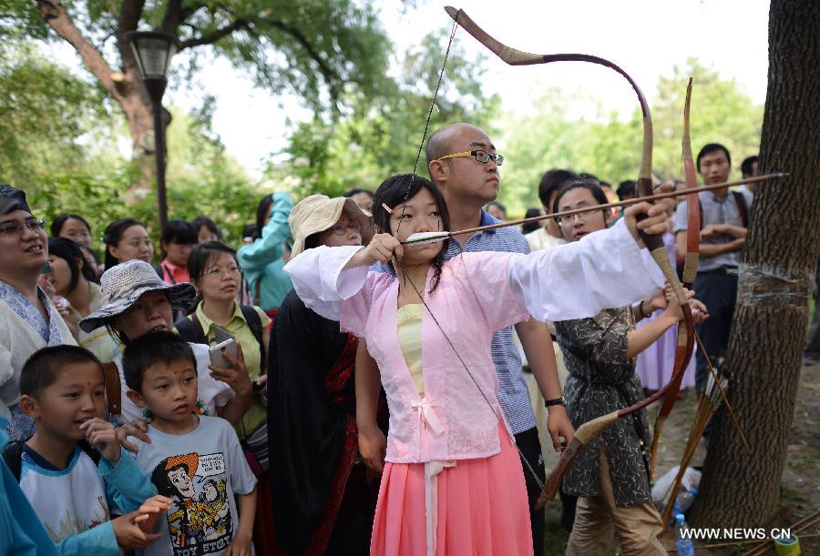 A girl wearing the archaic costumes typical of the Han Dynasty (202 BC - 221 AD) perform archery during an event to commemorate Quyuan, a famous ancient official who drowned himself for finding no way to make his small hinterland kingdom better, and spend the holiday of Dragon Boat Festival in Beijing, China, June 12, 2013. (Xinhua/Wang Jianhua)  