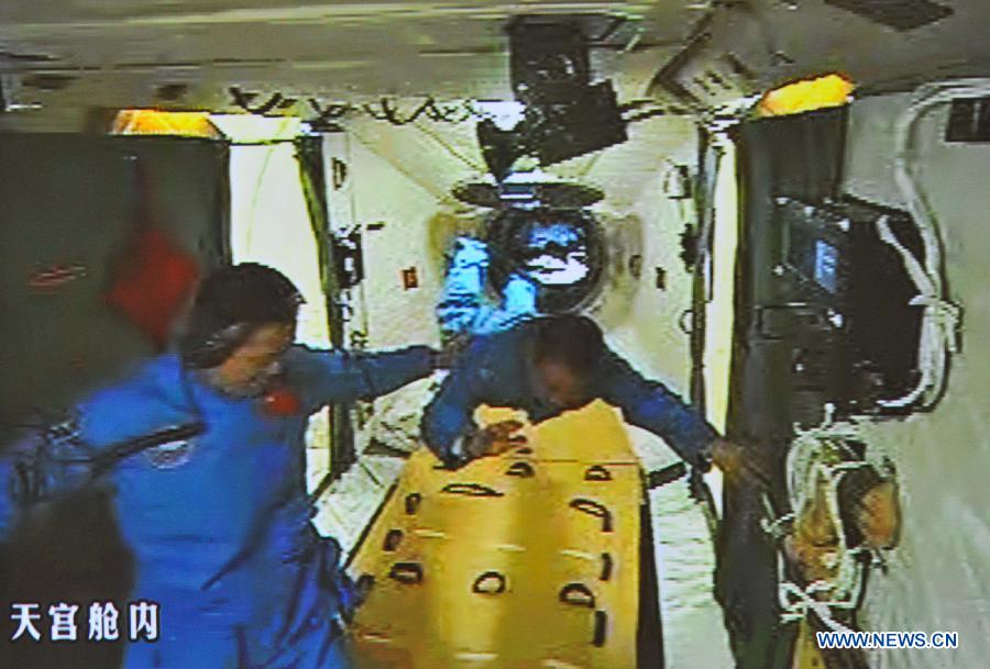 Photo taken on June 13, 2013 shows the screen at the Beijing Aerospace Control Center showing Nie Haisheng (L) helping Zhang Xiaoguang to stand after entering the Tiangong-1 space module. China's Shenzhou-10 manned spacecraft successfully completed an automated docking with the orbiting Tiangong-1 space module at 1:18 p.m. Thursday and the astronauts Nie Haisheng, Zhang Xiaoguang and Wang Yaping opened the hatch of Tiangong-1 at 4:17 p.m. (Xinhua/Liu Chan)