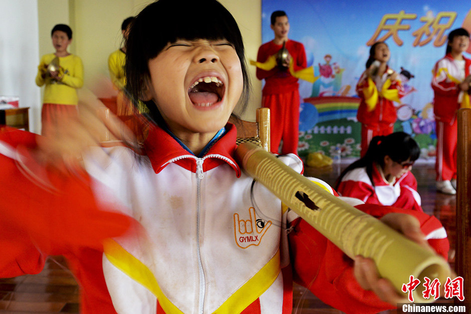 An Xingxing, 9, the youngest player in the team, practices percussion. It was the third bamboo tube that she has broken. (Chinanews/Zhang Yuan)