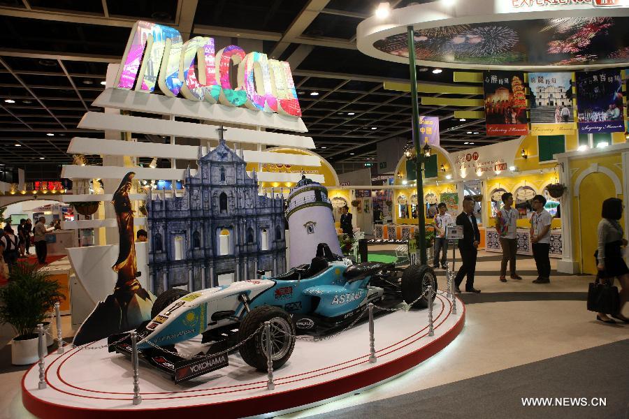 People walk past a racing car displayed at the exhibition stand of south China's Macau during the 27th Hong Kong International Travel Expo in south China's Hong Kong, June 13, 2013. The four-day expo kicked off here on Thursday at Hong Kong Convention & Exhibition Centre. (Xinhua/Wong Pun Keung)
