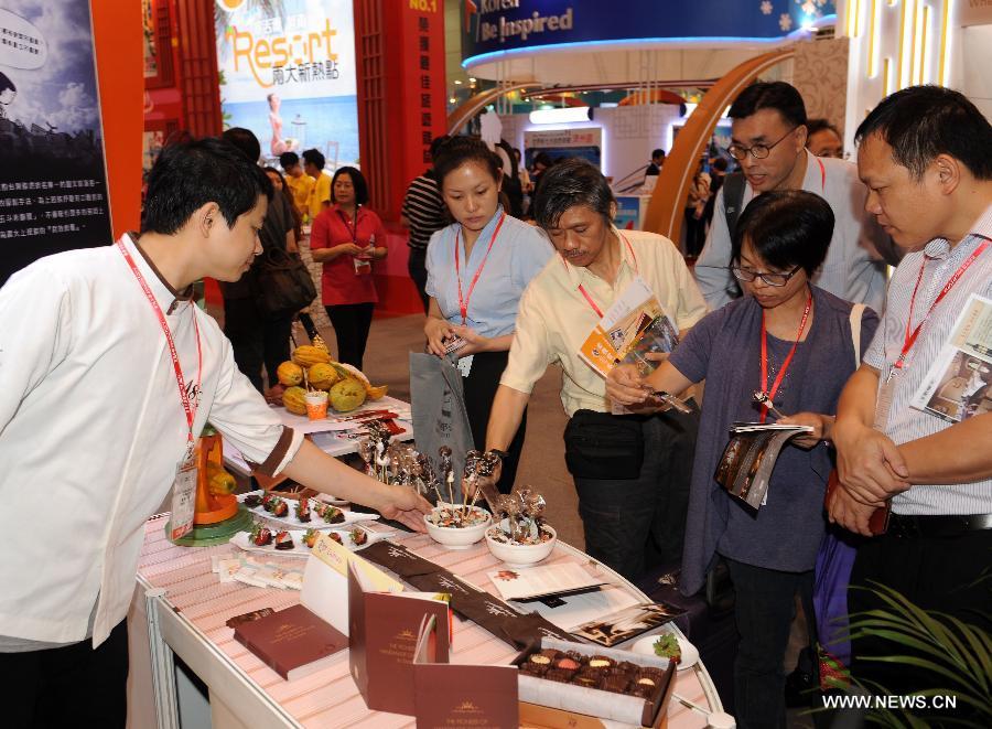 People taste food at an exhibition stand from southeast China's Taiwan at the 27th Hong Kong International Travel Expo in south China's Hong Kong, June 13, 2013. The four-day expo kicked off here on Thursday at Hong Kong Convention & Exhibition Centre. (Xinhua/Wong Pun Keung)