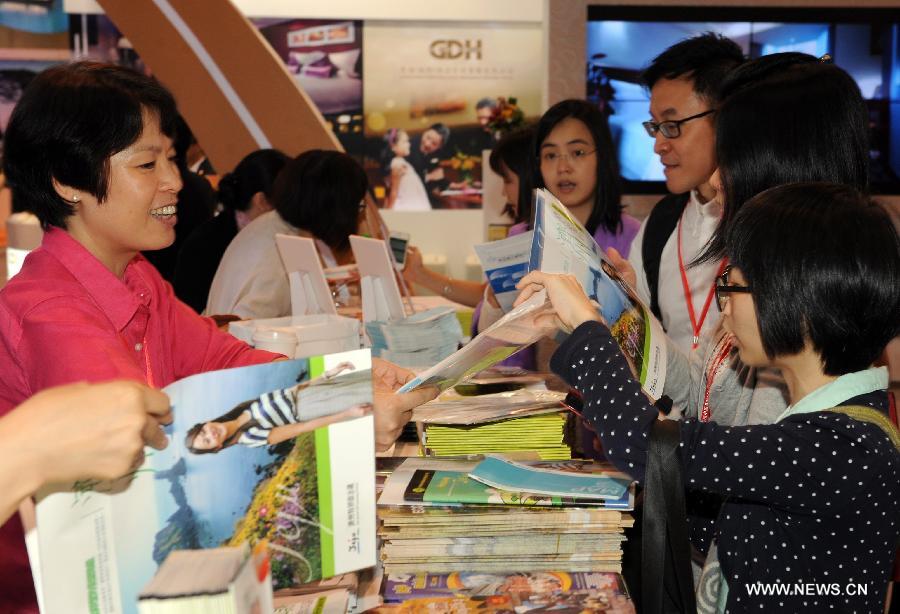 People get tourist handbooks at the exhibition stand of Jeju Island in South Korea during the 27th Hong Kong International Travel Expo in south China's Hong Kong, June 13, 2013. The four-day expo kicked off here on Thursday at Hong Kong Convention & Exhibition Centre. (Xinhua/Wong Pun Keung)