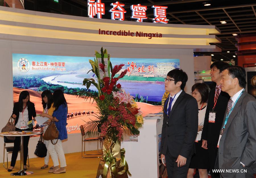 People walk past an exhibition stand of northwest China's Ningxia Hui Autonomous Region at the 27th Hong Kong International Travel Expo in south China's Hong Kong, June 13, 2013. The four-day expo kicked off here on Thursday at Hong Kong Convention & Exhibition Centre. (Xinhua/Wong Pun Keung)
