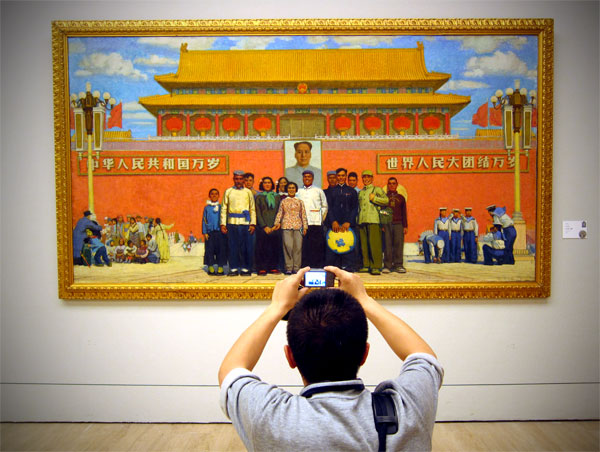 A man takes the classic tourist shot of Sun Zixi's painting "In Front of Tiananmen." [Photo: CRIENGLISH.com/William Wang]        