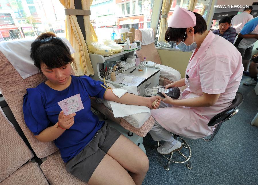 A woman donates her blood for free in a voluntary blood donation house in Yinchuan, capital of Ningxia Hui Autonomous Region, June 14, 2013. June 14 is the World Blood Donor Day. Many citizens in Yinchuan donated their blood for free on the streets of Yinchuan on Friday. (Xinhua/Peng Zhaozhi)  