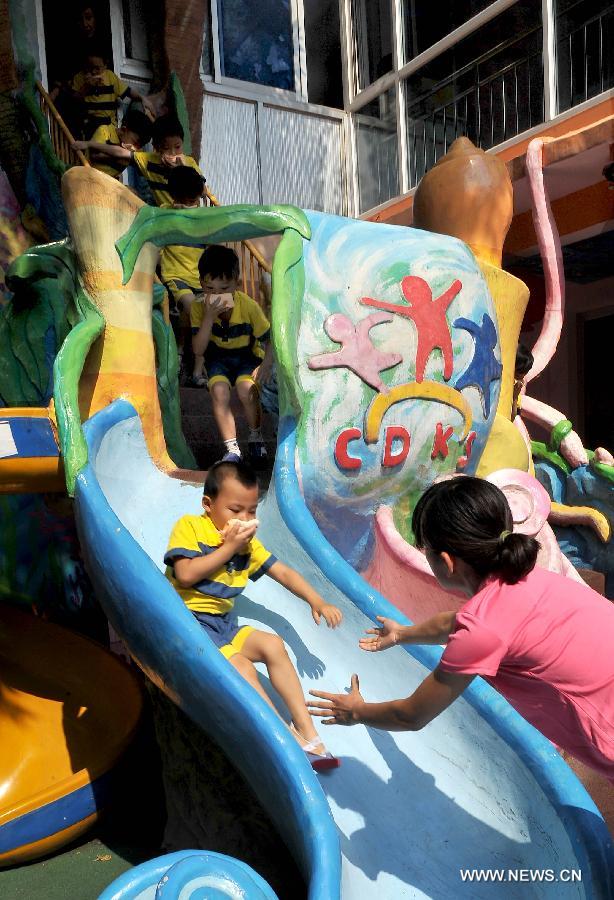 Children take part in a emergent evacuation drill using a sliding board in a kindergarten in Huaiyin District of Jinan, capital of east China's Shandong Province, June 14, 2013. Kindergartens in Huaiyin District held emergent fire fighting drills on Friday, in an aim to improve children and staff's ability to prevent fires, save themselves and cooperate with others. (Xinhua/Zhu Zheng)