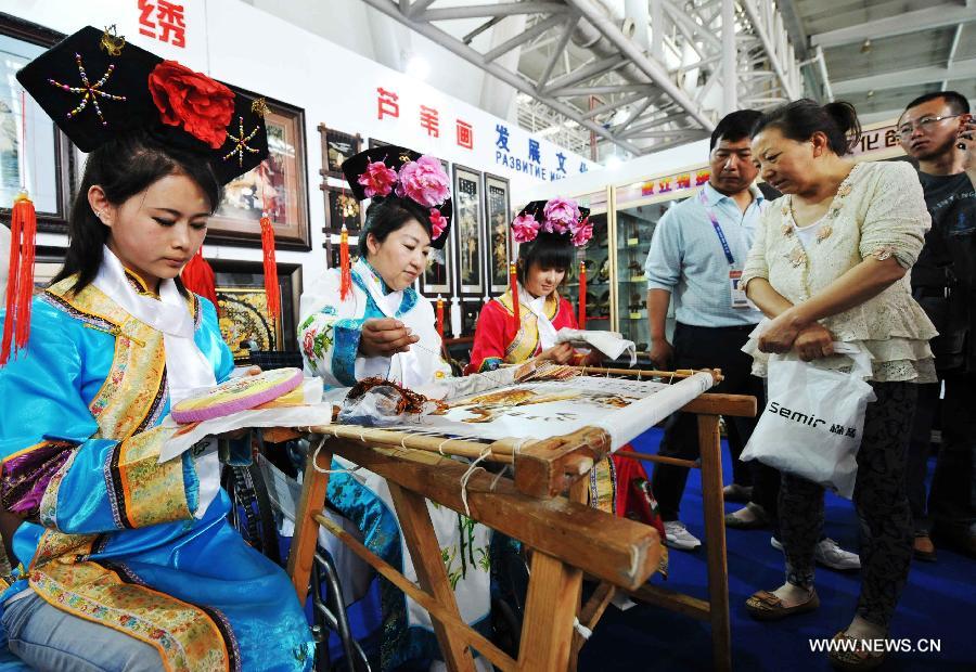 Visitors view the embroidery works in style of the Man ethnic group at the 24th China Harbin International Economic and Trade Fair in Harbin, capital of northeast China's Heilongjiang Province, June 15, 2013. A total of 9,335 exhibitors from 75 countries and regions took part in the fair. (Xinhua/Wang Jianwei)