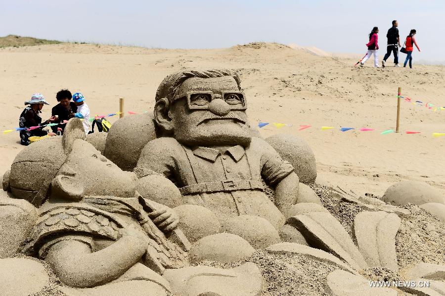 Visitors pass by an artwork of sand sculpture during a tourism promotion event held at the scenery spot of the Qinghai Lake in northwest China's Qinghai Province, June 15, 2013. (Xinhua/Zhang Hongxiang) 