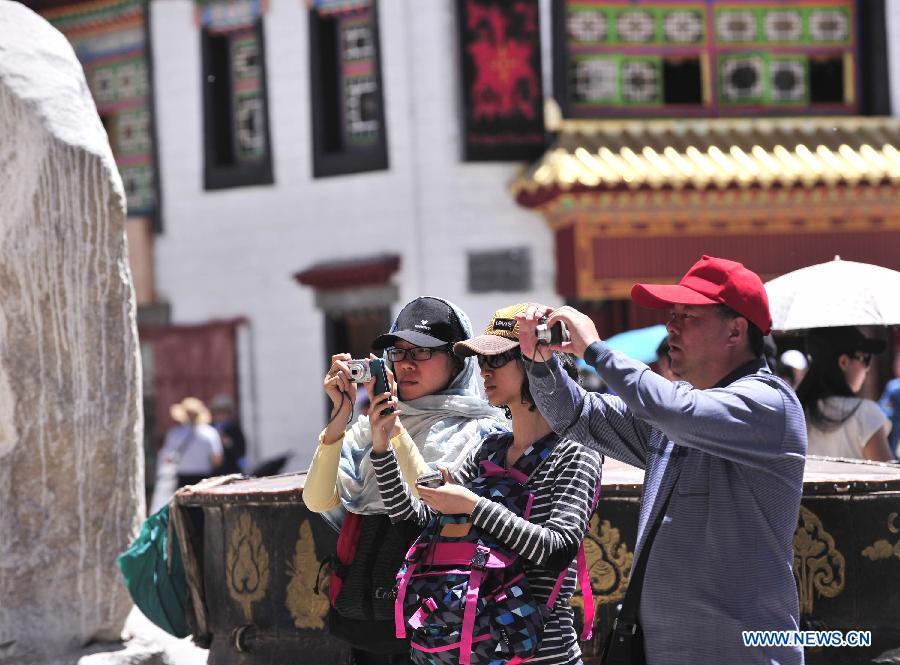 Visitors take pictures outside the Jokhang Temple in Lhasa, capital of southwest China's Tibet Autonomous Region, June 15, 2013. Lhasa has accepted more than 1 million people from January to May in 2013 and witnessed a tourism income of 1.033 billion yuan (about 165.28 million U.S. dollars ), making year on year increase of 35.86 percent and 49.35 percent respectively. (Xinhua/Liu Kun)