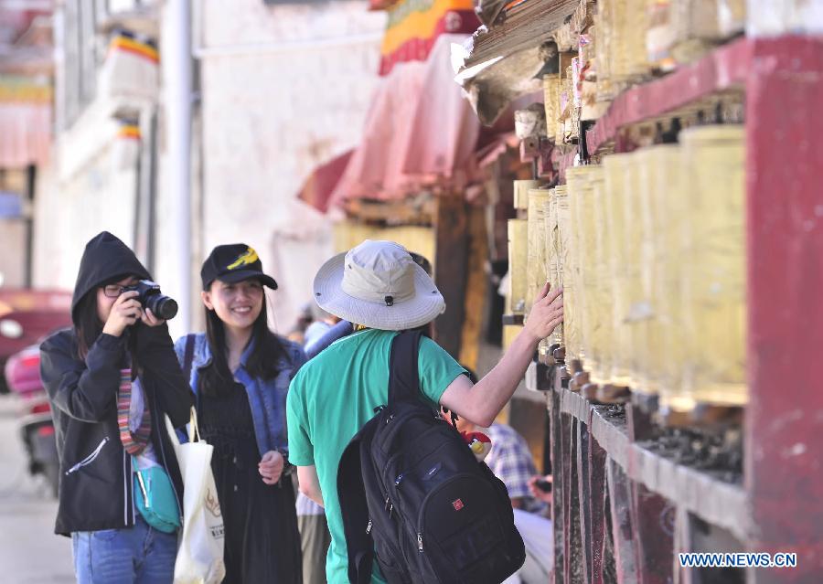 A visitor poses for photos on the Barkhor Street in Lhasa, capital of southwest China's Tibet Autonomous Region, June 15, 2013. Lhasa has accepted more than 1 million people from January to May in 2013 and witnessed a tourism income of 1.033 billion yuan (about 165.28 million U.S. dollars ), making year on year increase of 35.86 percent and 49.35 percent respectively. (Xinhua/Liu Kun)