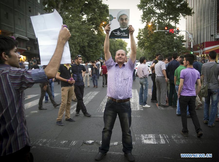 A man holds a poster of Iran's former nuclear negotiator Hassan Rouhani to celebrate his victory at the presidential election on a street in Tehran, Iran, June 15, 2013. Hassan Rouhani defeated his rival conservative candidates in Iran's 2013 presidential election Saturday by gaining 18,613,329 votes out of counted votes of 36,704,156, accounting for 50.7 percent of all the votes, with a turnout rate of 72.2 percent. (Xinhua/Ahmad Halabisaz) 