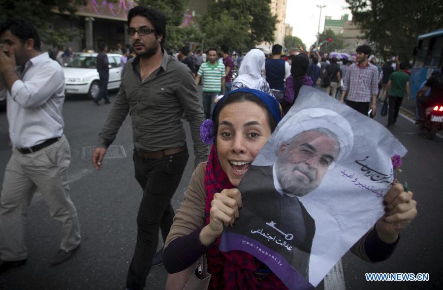 A woman shows a poster of Iran's former nuclear negotiator Hassan Rouhani to celebrate his victory at the presidential election on a street in Tehran, Iran, June 15, 2013. Hassan Rouhani defeated his rival conservative candidates in Iran's 2013 presidential election Saturday by gaining 18,613,329 votes out of counted votes of 36,704,156, accounting for 50.7 percent of all the votes, with a turnout rate of 72.2 percent. (Xinhua/Ahmad Halabisaz) 