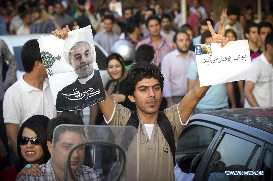 A man raises a poster of Iran's former nuclear negotiator Hassan Rouhani to celebrate his victory at the presidential election on a street in Tehran, Iran, June 15, 2013. Hassan Rouhani defeated his rival conservative candidates in Iran's 2013 presidential election Saturday by gaining 18,613,329 votes out of counted votes of 36,704,156, accounting for 50.7 percent of all the votes, with a turnout rate of 72.2 percent. (Xinhua/Ahmad Halabisaz) 