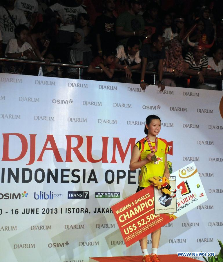 Li Xuerui of China presents her gold medal on the podium after winning the women's singles final match against Juliane Schenk of Germany at the Djarum Indonesia Open 2013 in Jakarta, Indonesia, June 16, 2013. Li Xuerui won 2-1. (Xinhua/Agung Kuncahya B)