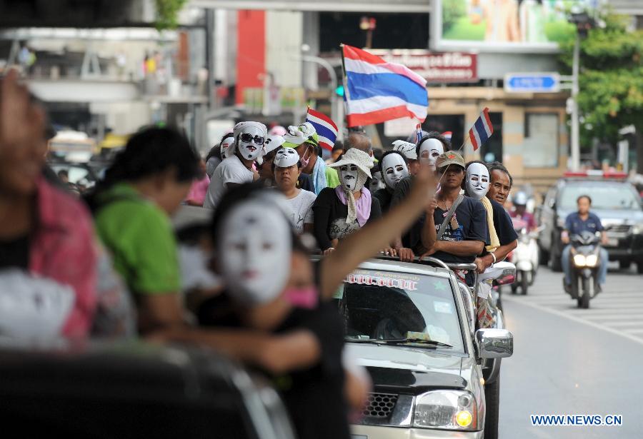 Protesters wearing masks shout slogans and hold up national flags as they march though a shopping district in Bangkok, capital of Thailand, on June 16, 2013. Thousands of protesters wearing masks held placards and shouted slogans against the government led by of Prime Minister Yingluck Shinawatra and her brother, former prime minister Thaksin Shinawatra. (Xinhua/Gao Jianjun) 