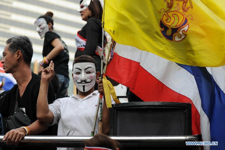 Protesters wearing masks shout slogans and hold up national flags as they stage an anti-government rally in a shopping district in Bangkok, capital of Thailand, on June 16, 2013. Thousands of protesters wearing masks held placards and shouted slogans against the government led by of Prime Minister Yingluck Shinawatra and her brother, former prime minister Thaksin Shinawatra. (Xinhua/Gao Jianjun) 