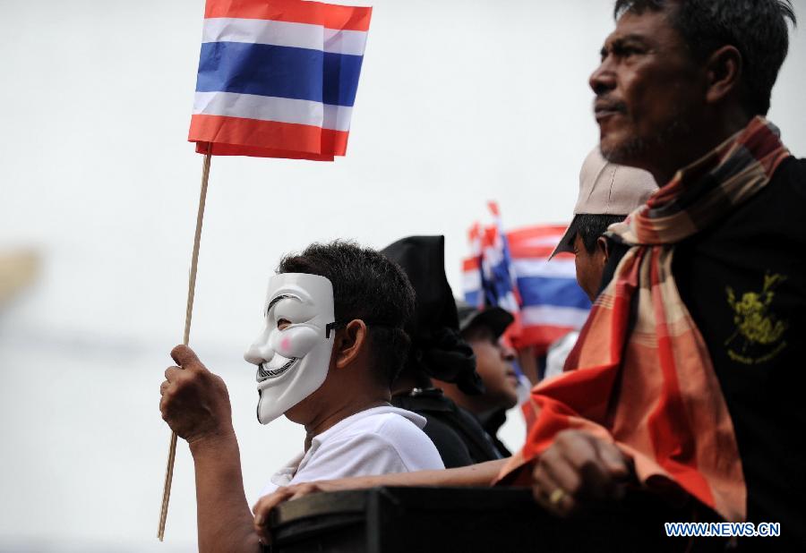 A Protesters wearing a mask holds up national flags as protesters stage an anti-government rally in a shopping district in Bangkok, capital of Thailand, on June 16, 2013. Thousands of protesters wearing masks held placards and shouted slogans against the government led by of Prime Minister Yingluck Shinawatra and her brother, former prime minister Thaksin Shinawatra. (Xinhua/Gao Jianjun) 