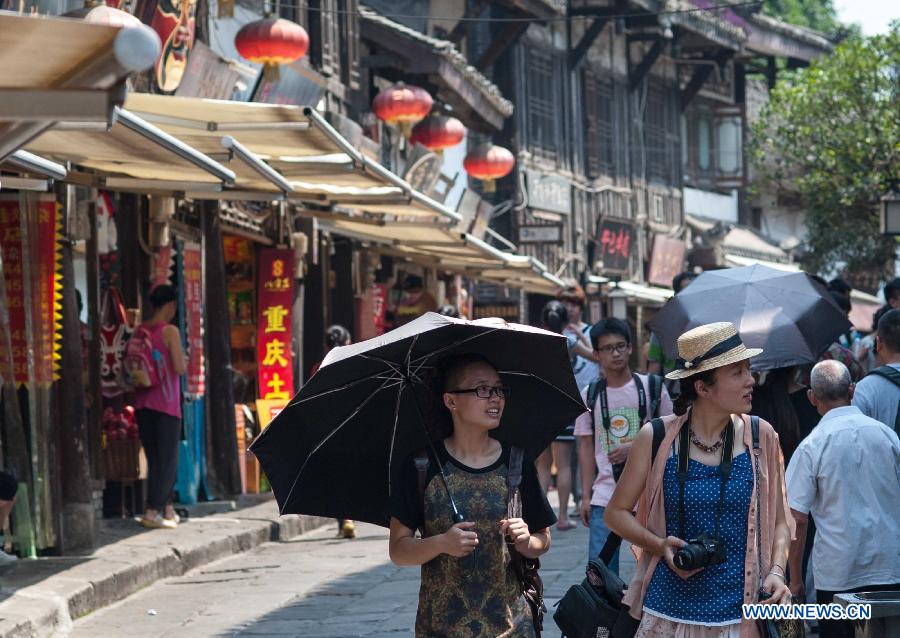 Tourists visit Ciqikou Town during a heat wave in Chongqing, southwest China's municipality, June 16, 2013. Local meteorological authorities issued an orange-coded alert of heat on Sunday, which indicates the temperature will rise up to 37 degrees Celsius Sunday afternoon. (Xinhua/Liu Chan)