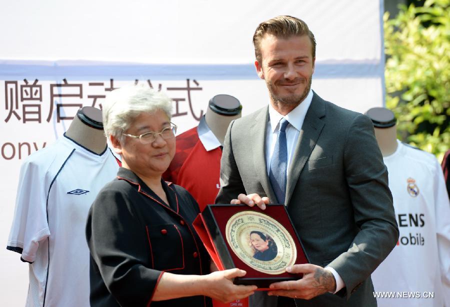 Recently retired football player David Beckham (R) recieves a souvenir during a donation ceremony in Beijing, capital of China, June 17, 2013. As the ambassador for the Football Programme in China and China's Super League, Beckham donated various team jerseys he wore during his career to a children's charity in China. David Beckham is joined by his wife Victoria during a seven day visit in China starting today. (Xinhua/Guo Yong) 