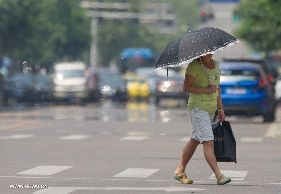 A woman walks under an umbrella on a street in southwest China's Chongqing Municipality, June 17, 2013. The highest temperature in Chongqing reached 39 degrees centigrade here on Monday. (Xinhua/Chen Cheng) 