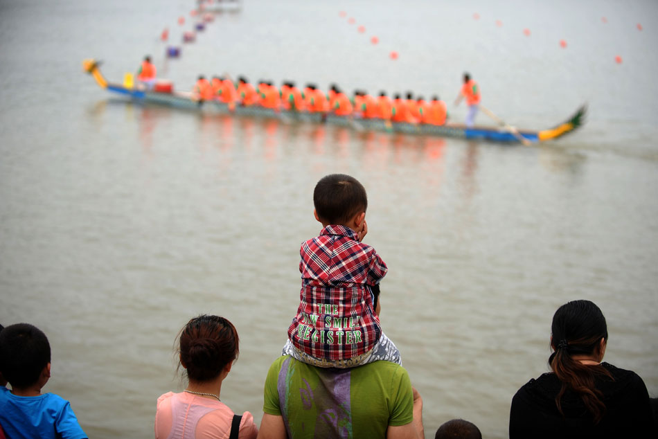 A boy sitting on father’s shoulders watches the dragon boat race held to embrace the Duanwu Festival, Qin county, central China’s Shanxi province, June 10, 2013. (Xinhua/Yan Yan)