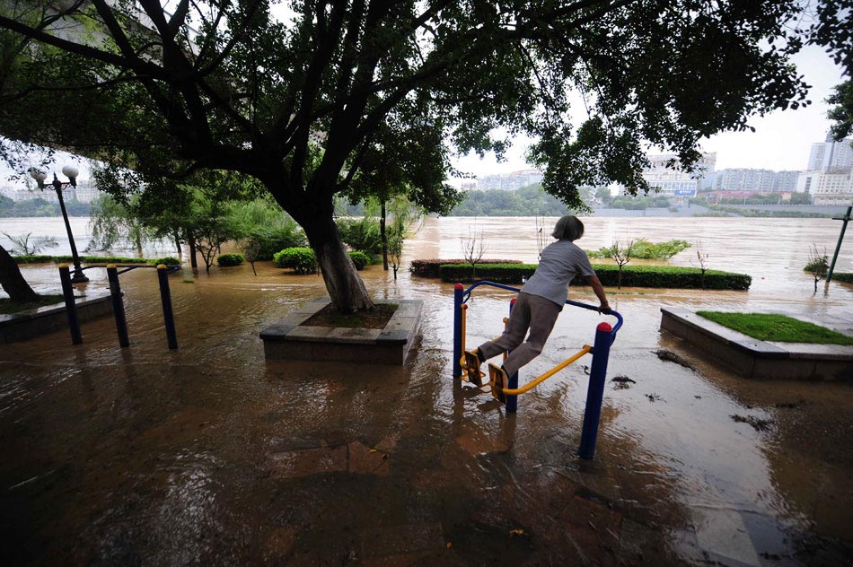 A woman uses fitness equipment to do exercise near the Liu River, southwest China’s Guangxi Zhuang autonomous region, June 10, 2013. After days of heavy rains, the water level of the river raised soon to the warning stage. (Xinhua/Huang Xiaobang)
