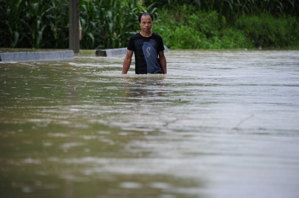 A man struggles to walk through a flooded street after a rainstorm, southwest China’s Guangxi Zhuang autonomous region, June 9, 2013. (Xinhua/Wu Yaorong)