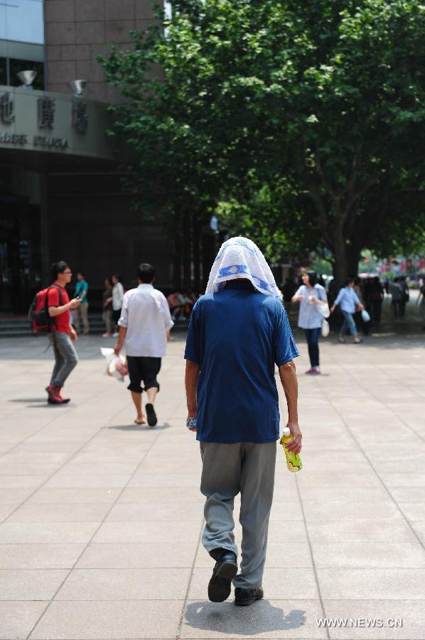 A pedestrian using a towel as a shelter walks on the Nanjing Road, a commercial street of east China's Shanghai Municipality, June 17, 2013. The highest temperature in Shanghai reached 36 degrees centigrade on Monday. (Xinhua/Liu Xiaojing) 