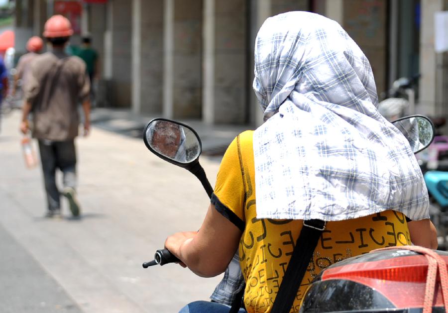 A citizen wearing scarf is seen in Yangzhou, east China's Jiangsu Province, June 17, 2013.The highest temperature in Yangzhou reached 36 degrees centigrade on June 17. (Xinhua/Zhuang Wenbin) 