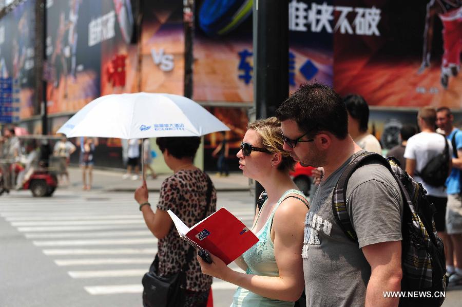 Tourists wearing sun glasses walk on Nanjing Road, a commercial street of east China's Shanghai Municipality, June 17, 2013. The highest temperature in Shanghai reached 36 degrees centigrade on Monday. (Xinhua/Liu Xiaojing) 