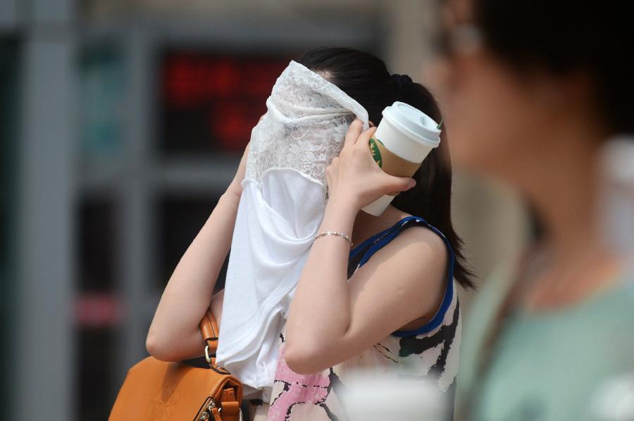 A girl holds her clothes for shelter in Yangzhou, east China's Jiangsu Province, June 17, 2013.The highest temperature in Yangzhou reached 36 degrees centigrade on June 17. (Xinhua/Meng Delong) 