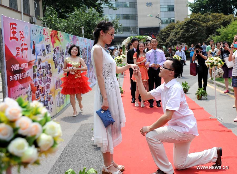Huang Changen (R), a postgraduate student of the School of Medicine of the Southeast University (SEU), makes a marriage proposal to his girlfriend at their graduation ceremony in Nanjing, capital of east China's Jiangsu Province, June 17, 2013. (Xinhua/Sun Can)