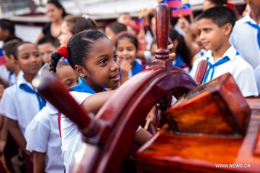 A Cuban school girl plays with the helm of Venezuelan Army School boat Simon Bolivar in Havana, capital of Cuba, June 17, 2013. This is the fourth visit of Simon Bolivar ship to Cuba. (Xinhua/Liu Bin)