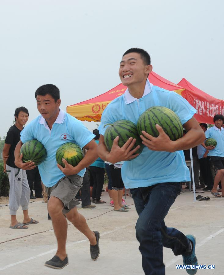 People participate in a running competition with holding watermelons during a watermelon festival in Fucheng County, north China's Hebei Province, June 18, 2013. The Fucheng County is a well-known watermelon growing area in north China, which grows 119,000 mu (about 8,000 hectares) watermelons and produces 550,000 tonnes of watermelons annually, with the annual sales volume reaching about 1 billion yuan (163.2 million U.S. dollars). (Xinhua/Wang Min)