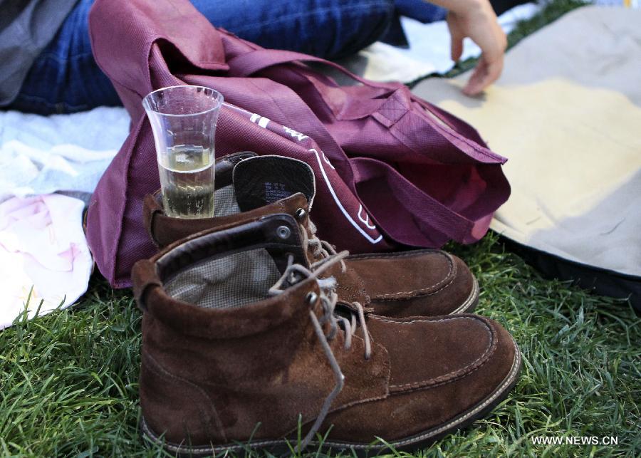 A cup of wine is seen in a shoe as people wait for watching a free outdoor film at Bryant Park in New York, the United States, June 17, 2013. There is a series of free outdoor films screening at Bryant Park every Monday from June 17 to August 19. (Xinhua/Cheng Li) 