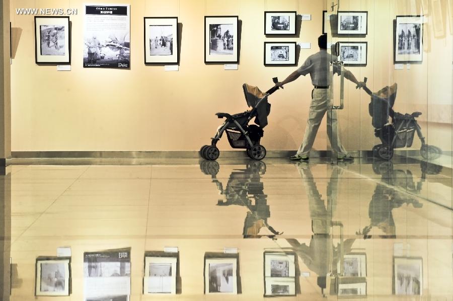 A man watches pictures during a photo exhibition displaying the works of Sidney D. Gamble in Beijing, capital of China, June 18, 2013. The exhibition displayed more than 100 photos taken by Gamble depicting the life of Beijing from 1908 to 1931. (Xinhua/Wang Jingsheng) 