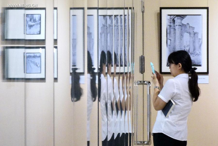 A citizen takes pictures during a photo exhibition displaying the works of Sidney D. Gamble in Beijing, capital of China, June 18, 2013. The exhibition displayed more than 100 photos taken by Gamble depicting the life of Beijing from 1908 to 1931. (Xinhua/Li Xin) 